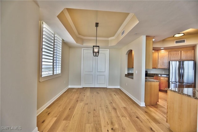 unfurnished dining area with crown molding, light hardwood / wood-style flooring, and a raised ceiling