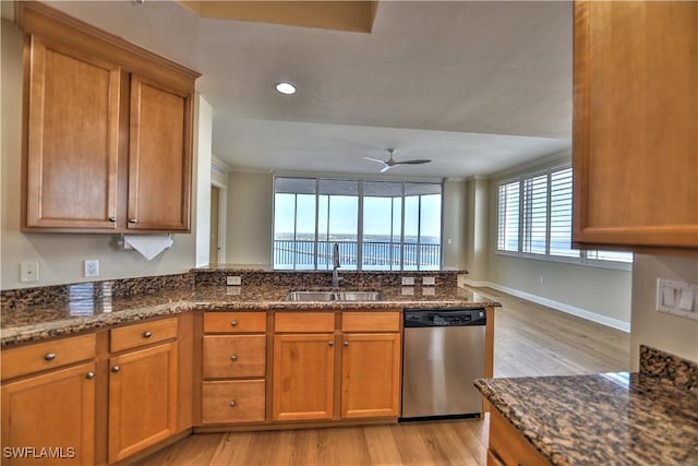 kitchen with sink, a water view, dishwasher, kitchen peninsula, and dark stone counters