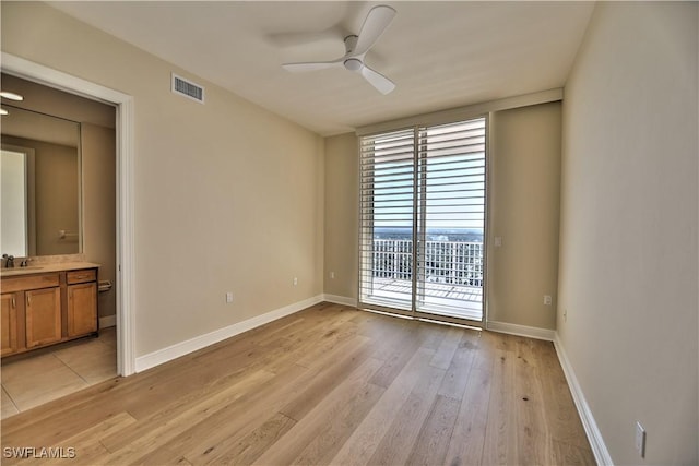 empty room featuring ceiling fan, sink, and light wood-type flooring