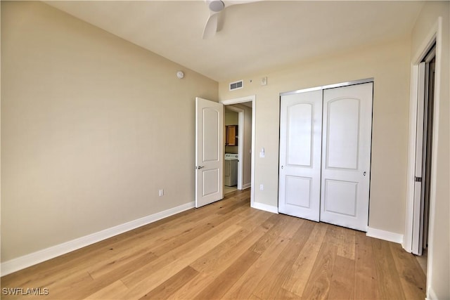 unfurnished bedroom featuring washer / dryer, light hardwood / wood-style flooring, ceiling fan, and a closet