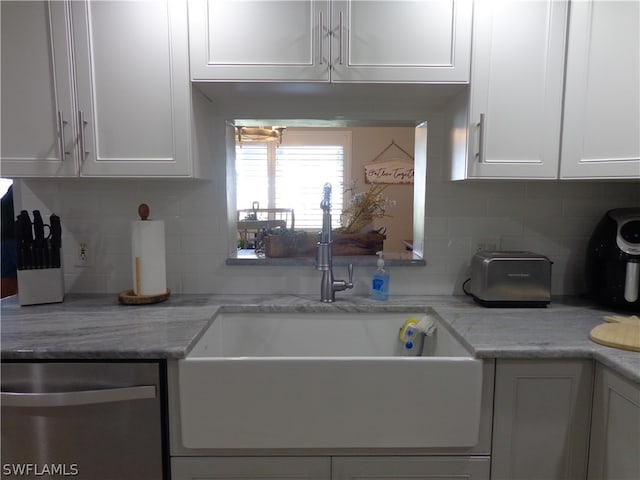 kitchen featuring white cabinetry, sink, light stone counters, dishwasher, and tasteful backsplash