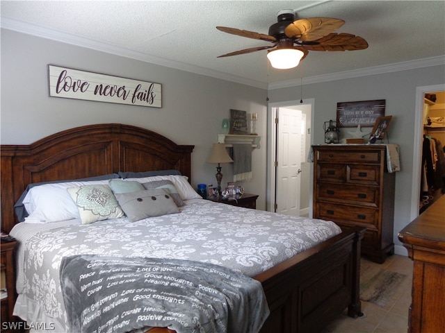 bedroom featuring light tile floors, a walk in closet, ceiling fan, and crown molding