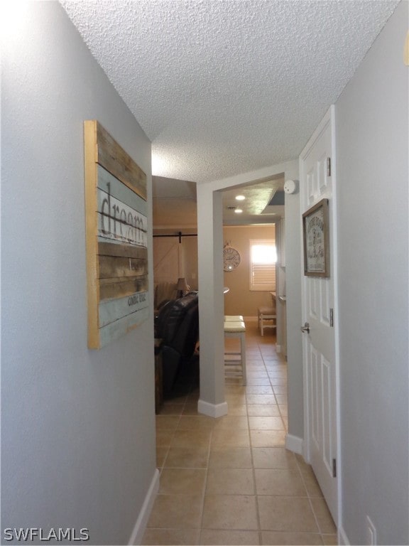 hallway with light tile floors and a textured ceiling