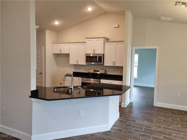 kitchen with white cabinets, appliances with stainless steel finishes, sink, lofted ceiling, and dark hardwood / wood-style floors