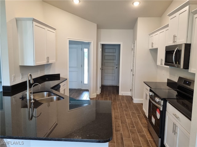 kitchen featuring white cabinets, dark stone countertops, stainless steel appliances, sink, and dark wood-type flooring