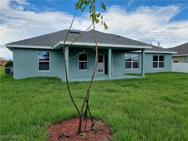 rear view of house with a yard, a patio, and central AC