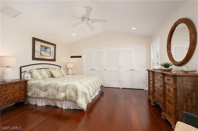 bedroom featuring multiple closets, ceiling fan, lofted ceiling, and dark hardwood / wood-style flooring