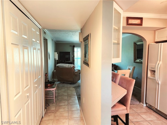 hallway with ornamental molding and light tile patterned floors