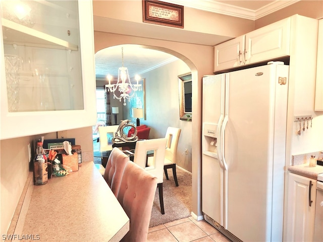 kitchen featuring ornamental molding, light tile patterned flooring, white refrigerator with ice dispenser, an inviting chandelier, and white cabinets