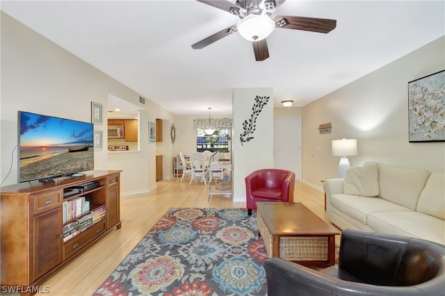 living room with ceiling fan with notable chandelier and light wood-type flooring