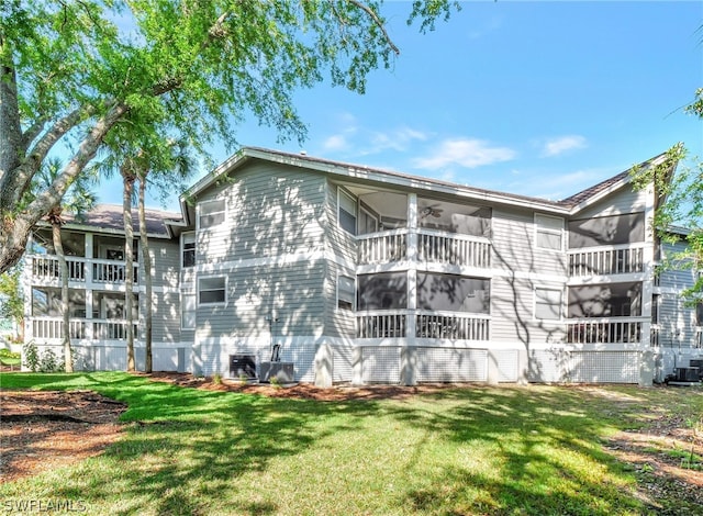 rear view of property with a balcony, central AC, and a lawn