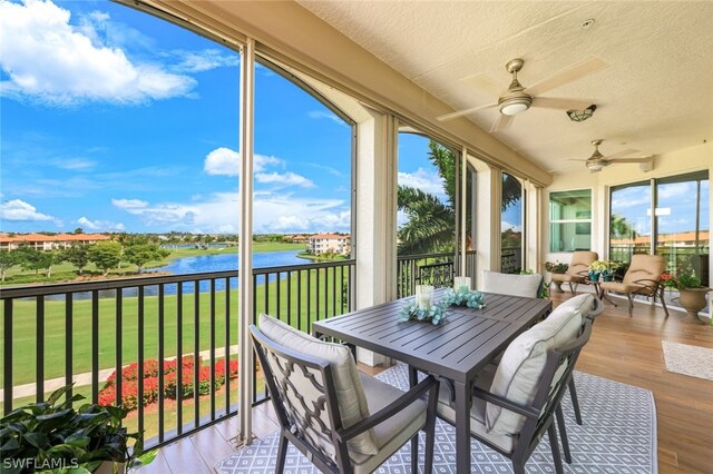 sunroom / solarium featuring a water view and ceiling fan