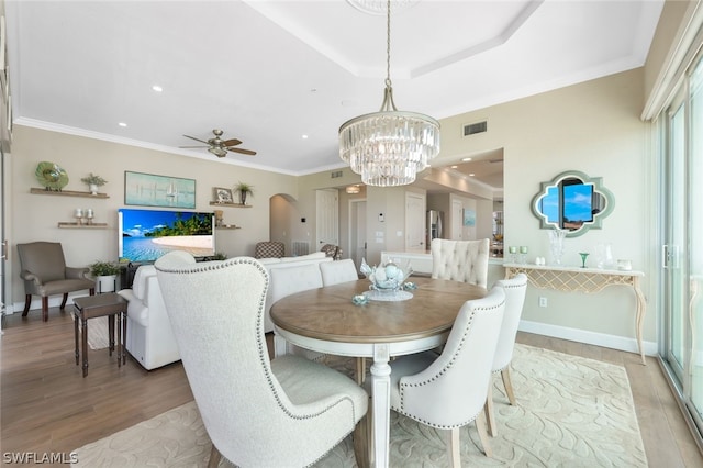 dining area featuring wood-type flooring, ceiling fan with notable chandelier, and ornamental molding