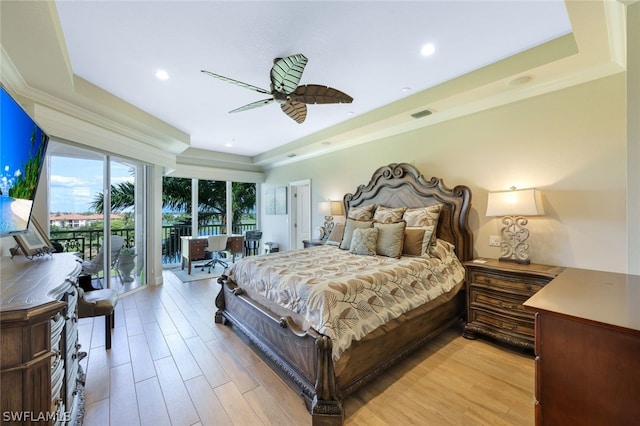 bedroom featuring light wood-type flooring, access to outside, a raised ceiling, and ceiling fan