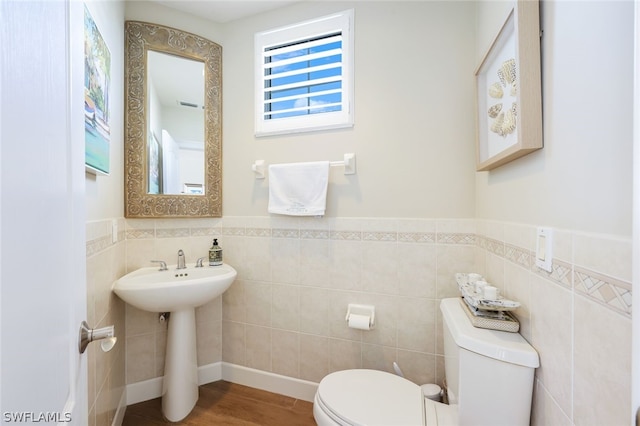 bathroom featuring hardwood / wood-style flooring, toilet, and tile walls