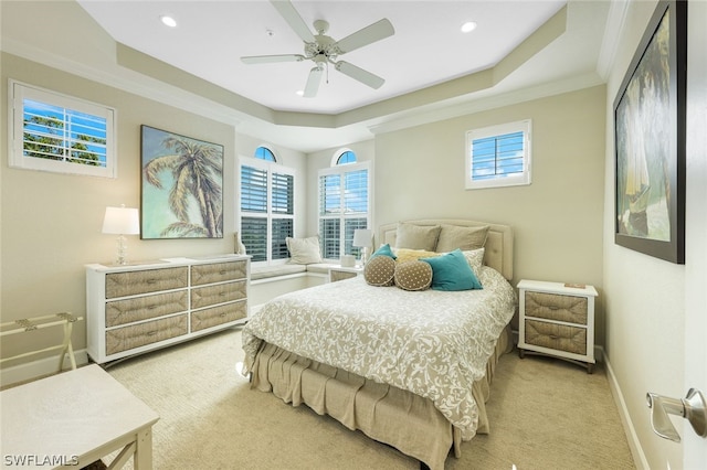 carpeted bedroom with a raised ceiling, multiple windows, and ceiling fan