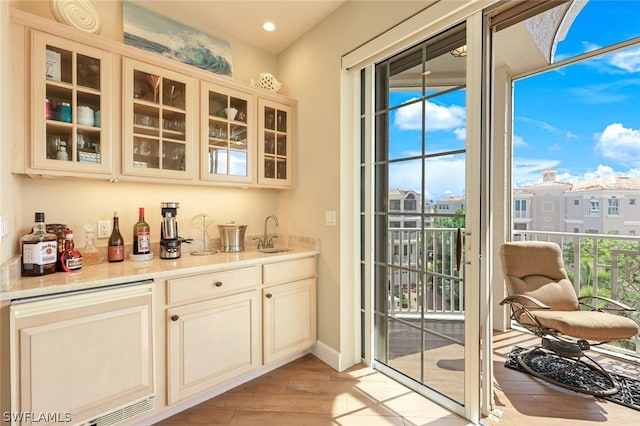 bar featuring sink, cream cabinetry, and light hardwood / wood-style flooring