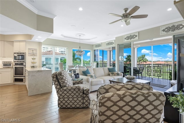 living room featuring crown molding, ceiling fan with notable chandelier, and light wood-type flooring