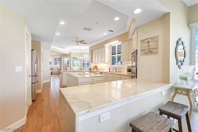 kitchen with kitchen peninsula, a center island, stainless steel appliances, and light stone counters