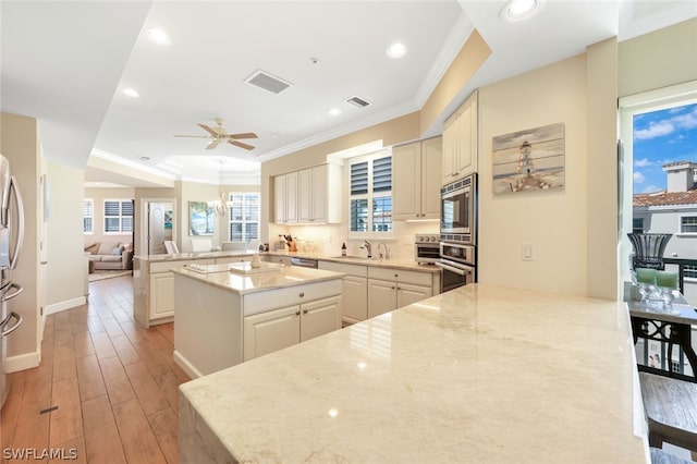 kitchen featuring kitchen peninsula, light stone countertops, light hardwood / wood-style floors, and appliances with stainless steel finishes