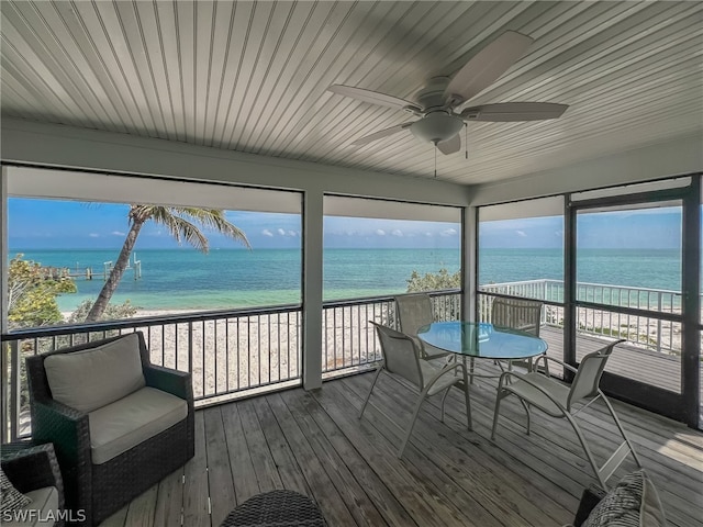 sunroom / solarium with ceiling fan and a water view