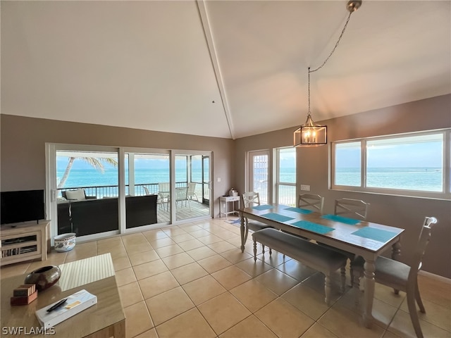 dining room with a chandelier, high vaulted ceiling, a water view, and light tile floors