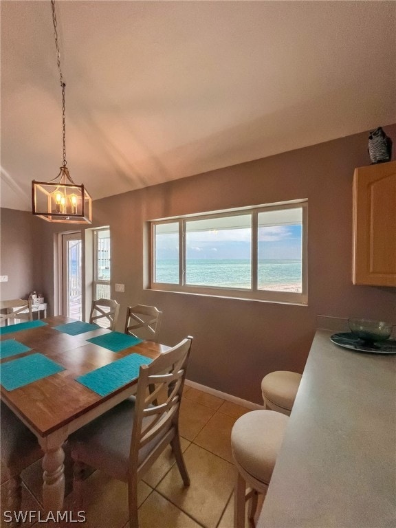 tiled dining room featuring a notable chandelier and vaulted ceiling