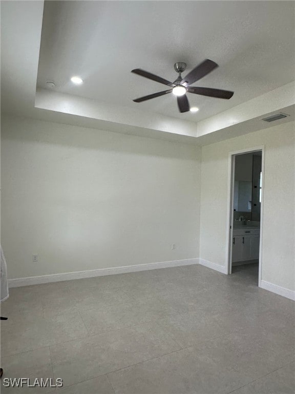 spare room featuring a tray ceiling and ceiling fan