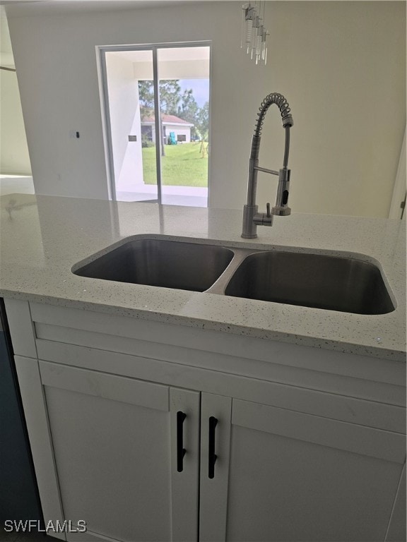 interior details featuring white cabinetry, sink, and light stone counters