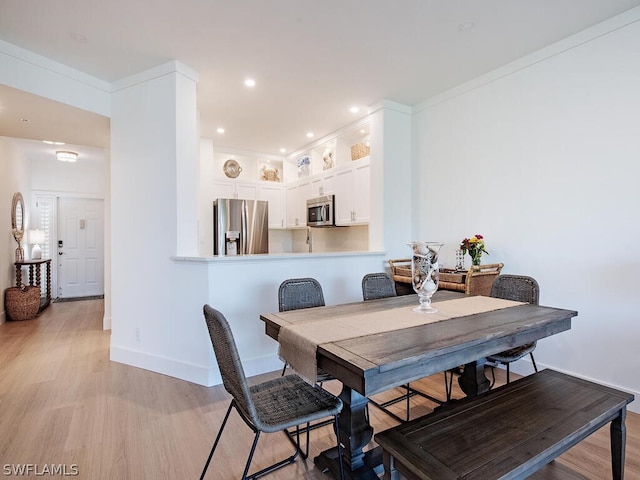 dining area with light wood-type flooring and ornamental molding