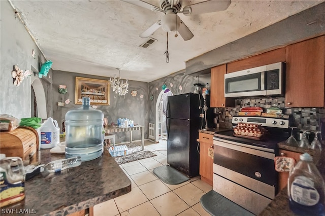 kitchen with hanging light fixtures, ceiling fan with notable chandelier, appliances with stainless steel finishes, and light tile floors