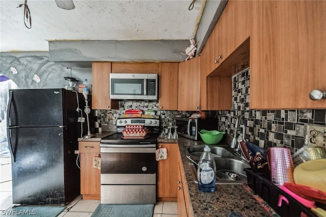 kitchen with sink, black refrigerator, backsplash, light tile flooring, and electric range oven