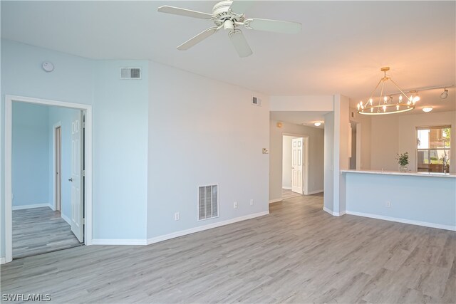 unfurnished living room with ceiling fan with notable chandelier and light wood-type flooring