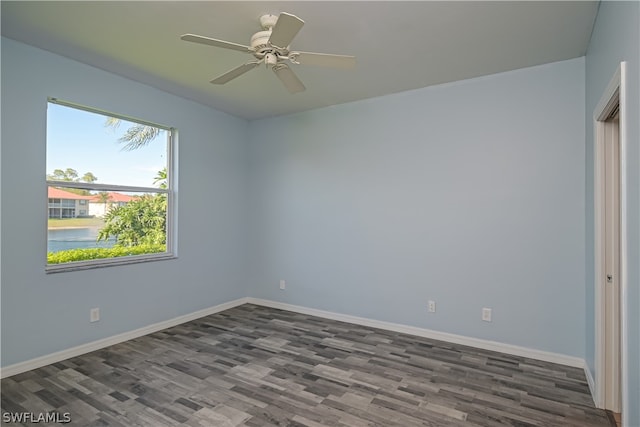 spare room featuring dark hardwood / wood-style floors, ceiling fan, and a water view