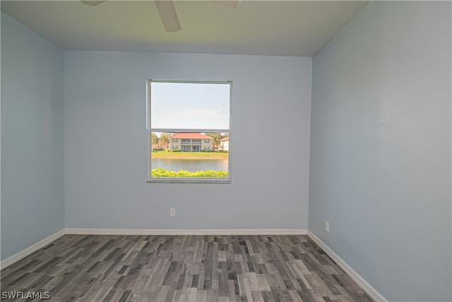 unfurnished room with a water view, ceiling fan, and dark hardwood / wood-style floors