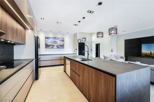 kitchen featuring an island with sink, stainless steel appliances, hanging light fixtures, light wood-type flooring, and sink