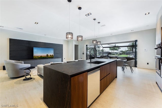 kitchen with an island with sink, dark stone counters, hanging light fixtures, dishwasher, and light wood-type flooring