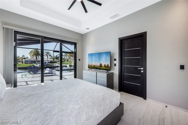 bedroom featuring ceiling fan, a tray ceiling, and access to exterior