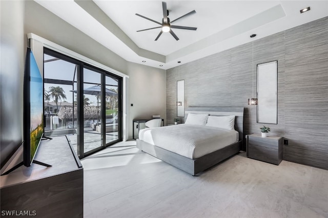 bedroom featuring a raised ceiling, access to exterior, and ceiling fan