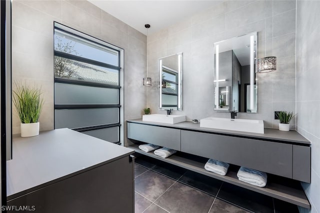 bathroom with tile walls, vanity with extensive cabinet space, dual sinks, and tile floors