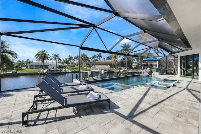 view of pool with glass enclosure, a patio, and a water view