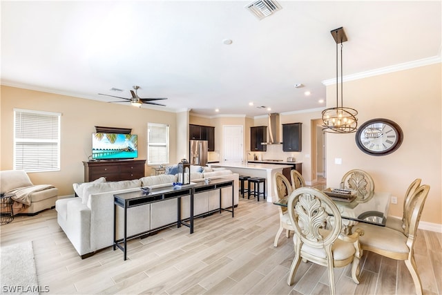 living room with ceiling fan with notable chandelier, light hardwood / wood-style floors, and crown molding