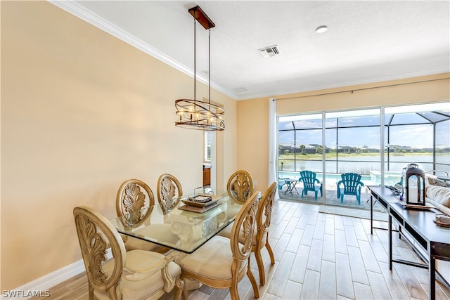 dining area with a water view, a notable chandelier, light hardwood / wood-style floors, and ornamental molding