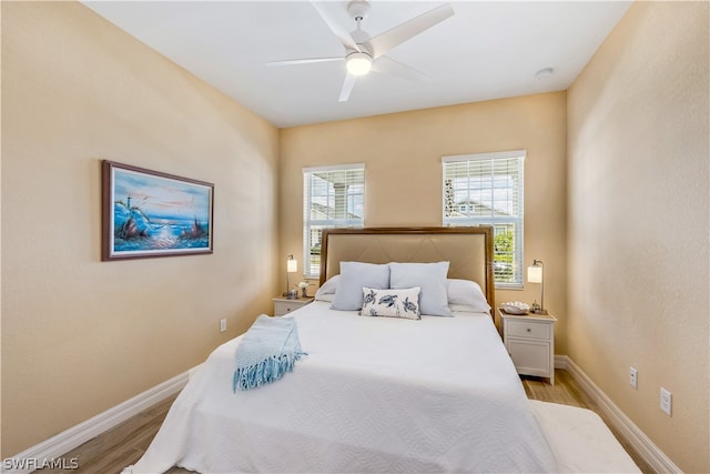 bedroom with ceiling fan, light hardwood / wood-style floors, and multiple windows