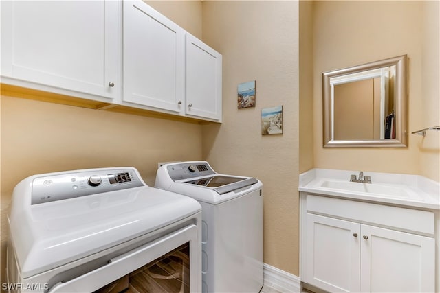 clothes washing area with cabinets, separate washer and dryer, and sink