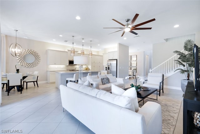 tiled living room with ceiling fan with notable chandelier