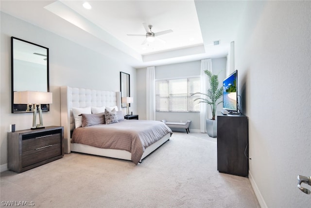 carpeted bedroom with ceiling fan and a tray ceiling