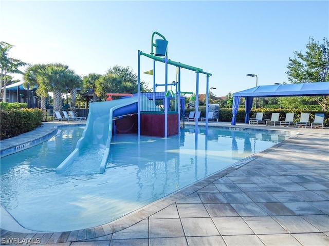 view of swimming pool featuring a playground and a water slide