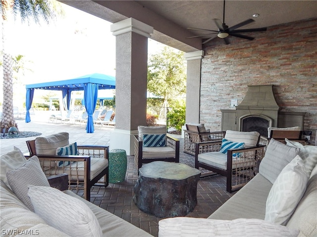 view of patio featuring ceiling fan and an outdoor living space with a fireplace