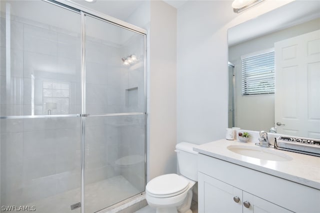 bathroom with a shower with door, vanity, and toilet